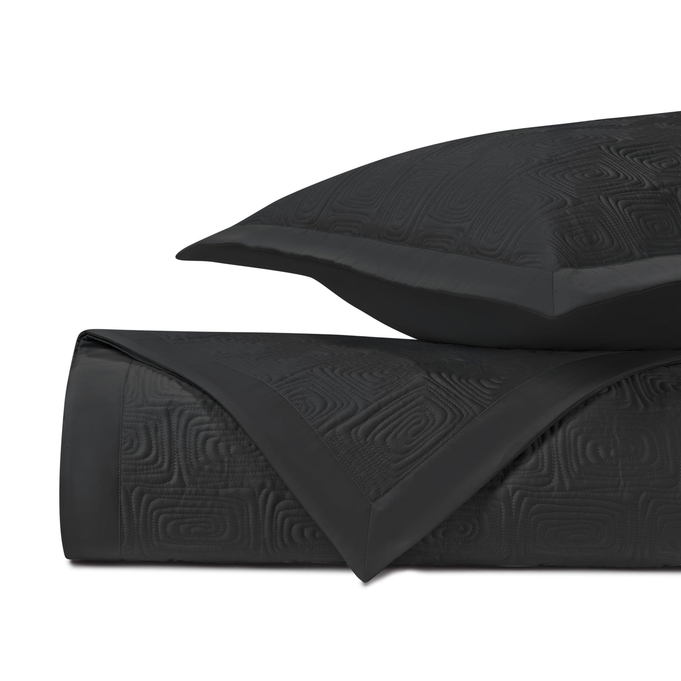 Folded onyx quilted coverlet and sham showing geometric maze-pattern texture.
