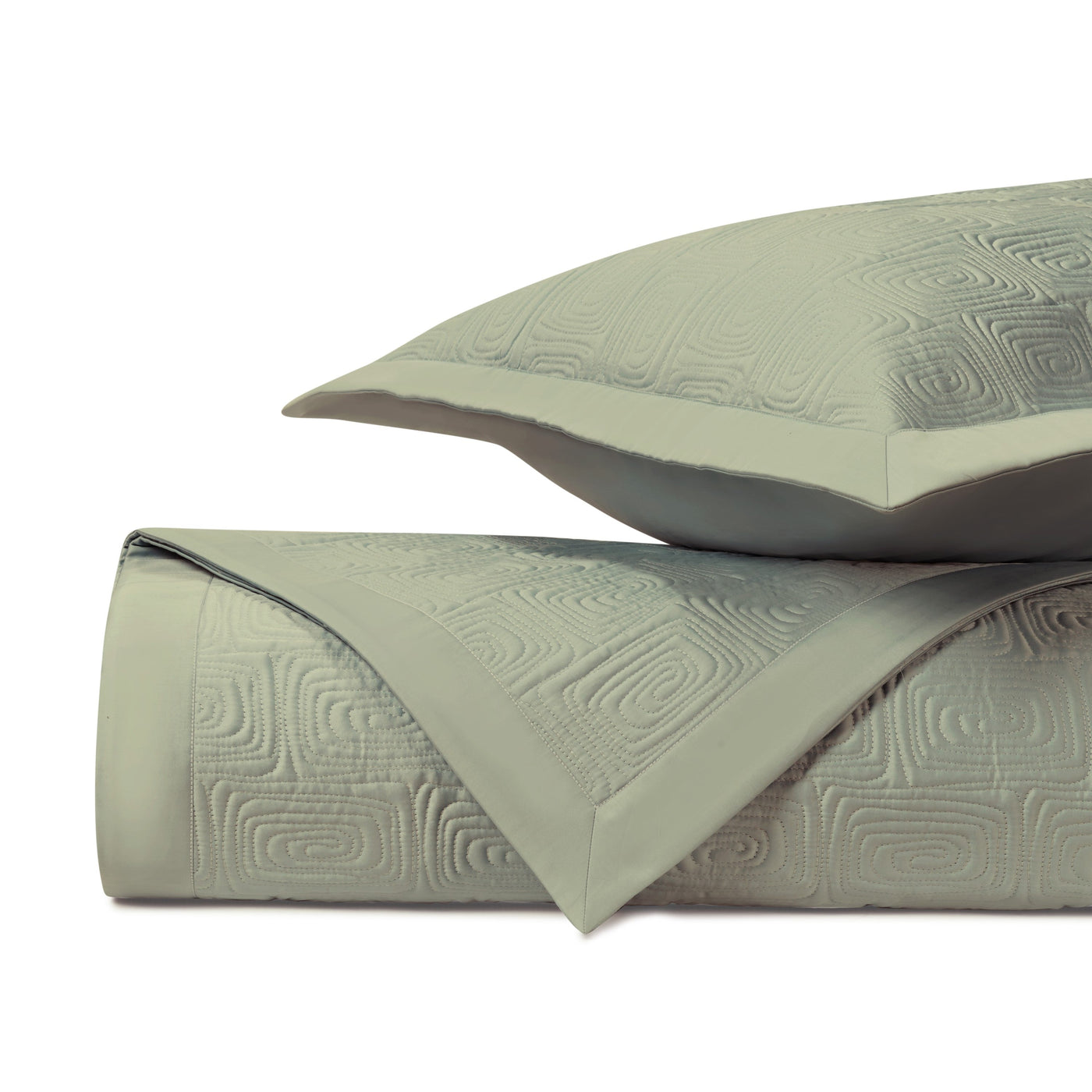 Close-up of sage green quilted cotton with geometric maze-pattern texture and satin border trim.