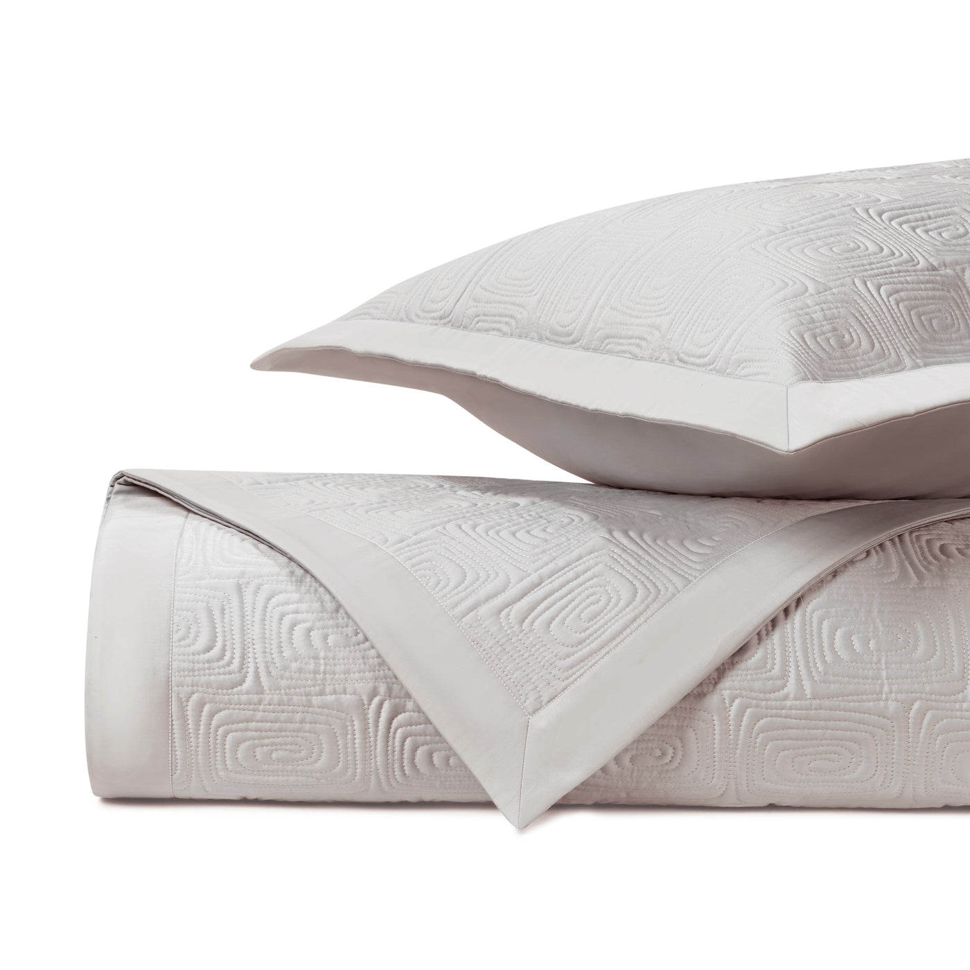 Close-up of ivory quilted matelassé with geometric maze pattern and contrast border.