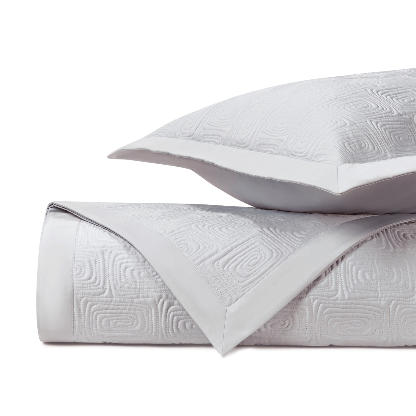Close-up of quilted geometric maze pattern on white matelassé fabric with border detail.
