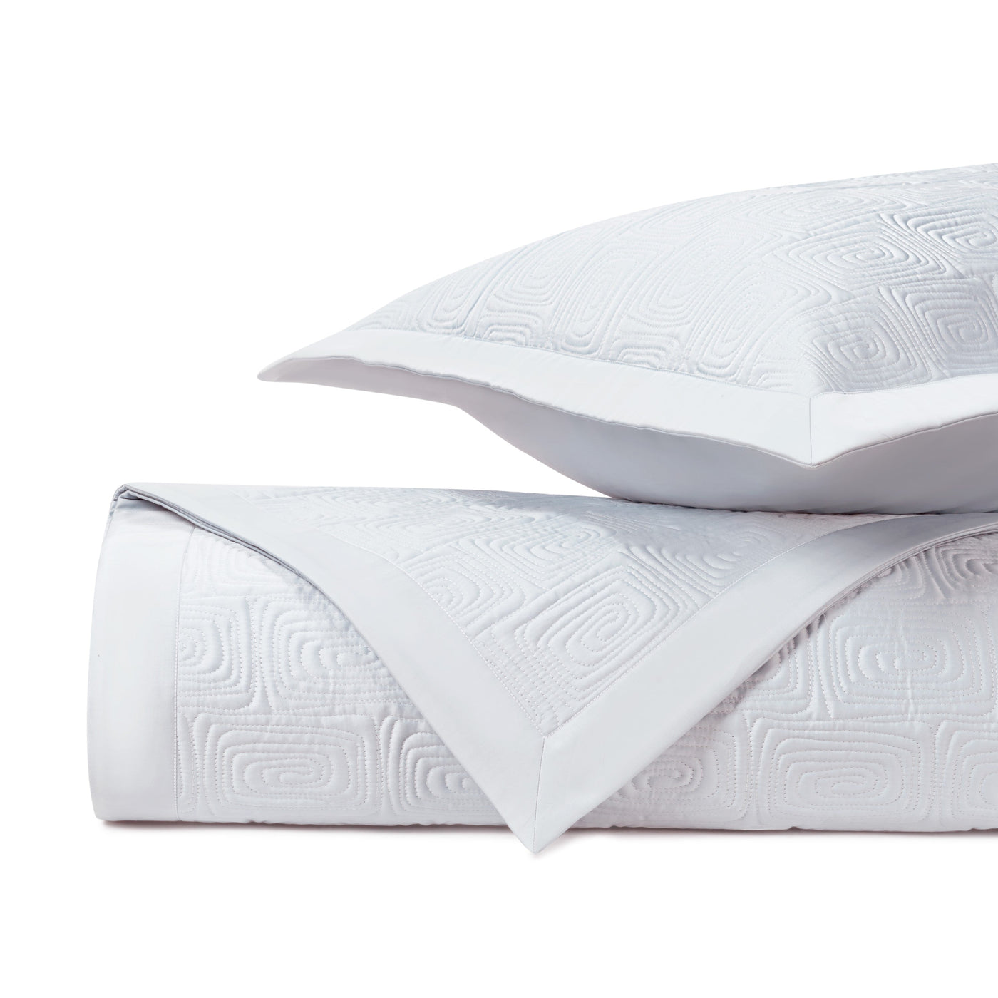 Close-up of Maze quilted texture in white with geometric relief pattern on folded coverlet and sham.
