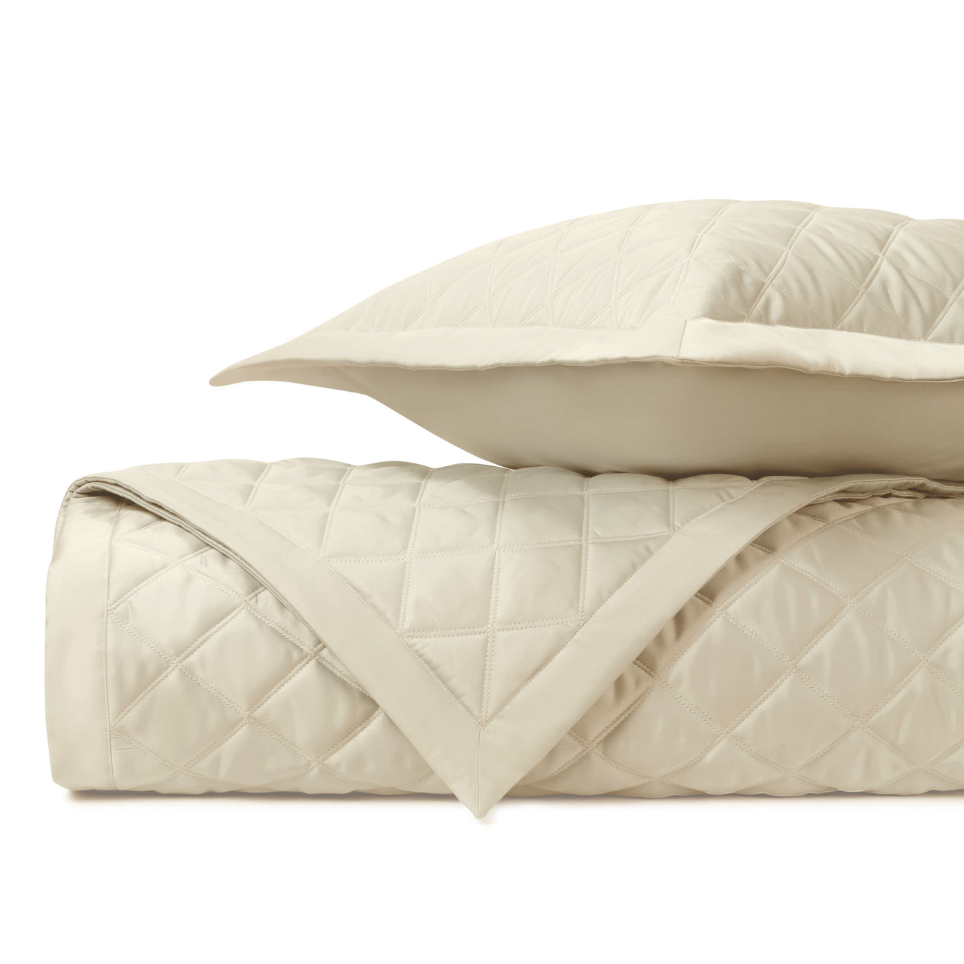 Close-up of ivory diamond-quilted cotton with satin border trim detail.