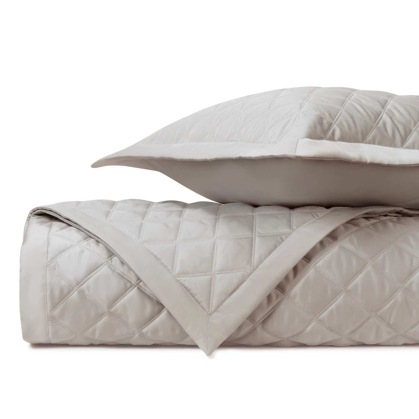 Close-up of diamond quilted satin in warm pearl, folded with matching sham.
