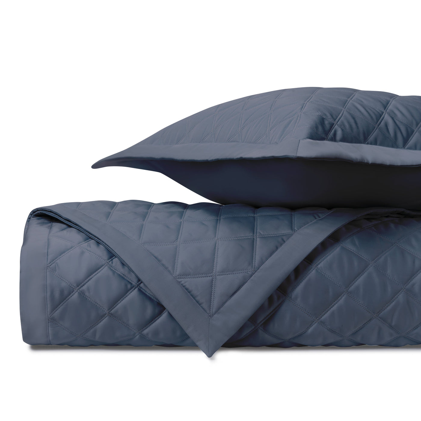 Close-up of navy blue diamond-quilted coverlet and sham, folded to show texture.