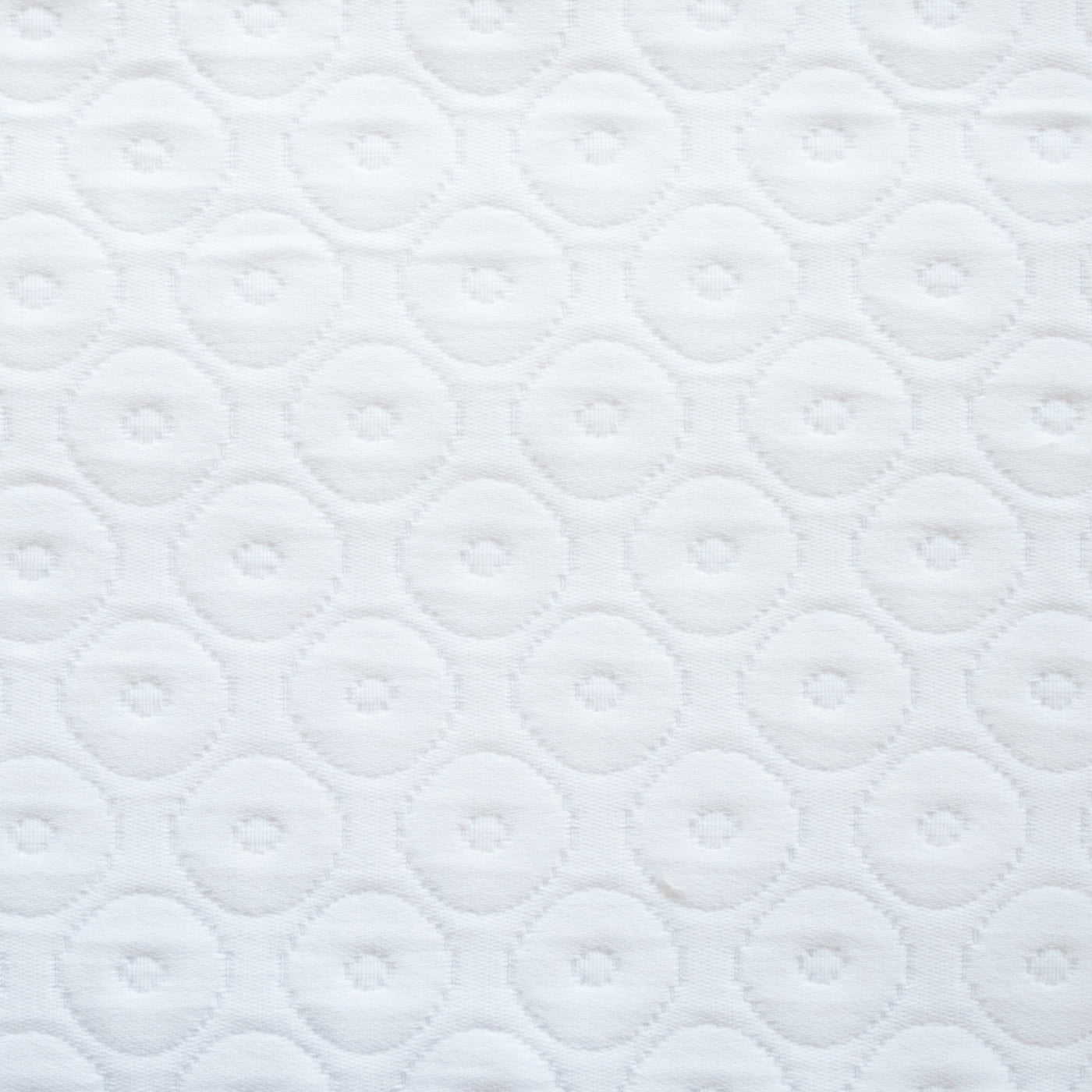 Close-up of white quilted fabric with tonal circular dot pattern.