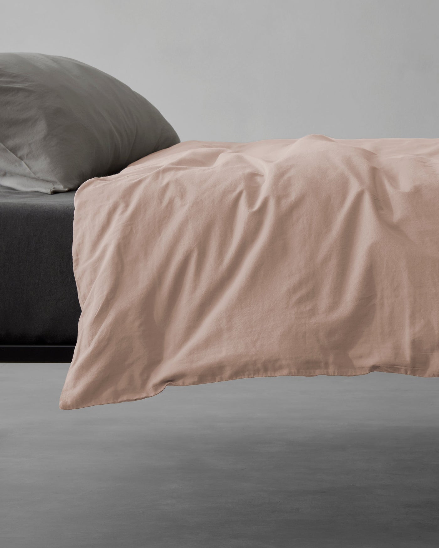 Close-up of Society Limonta Miro duvet cover in blush, draped over bed edge.