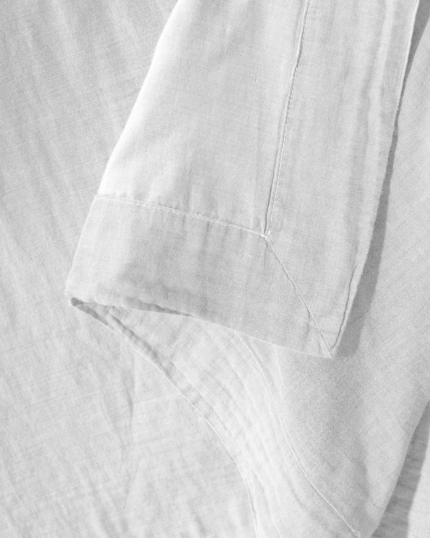 Close-up of white linen pillowcase hem stitching and folded edge detail.