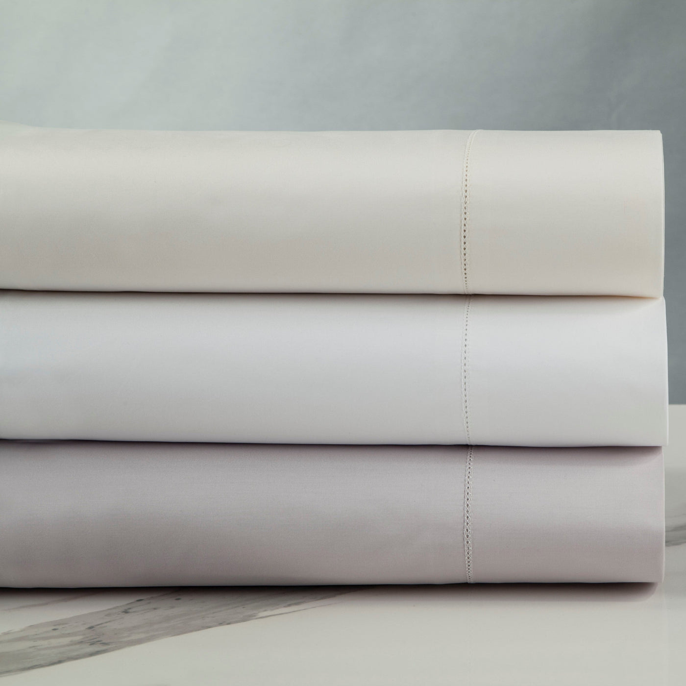 Three folded Home Treasures N°45 Classico sheets stacked in ivory, white, and lavender mist.
