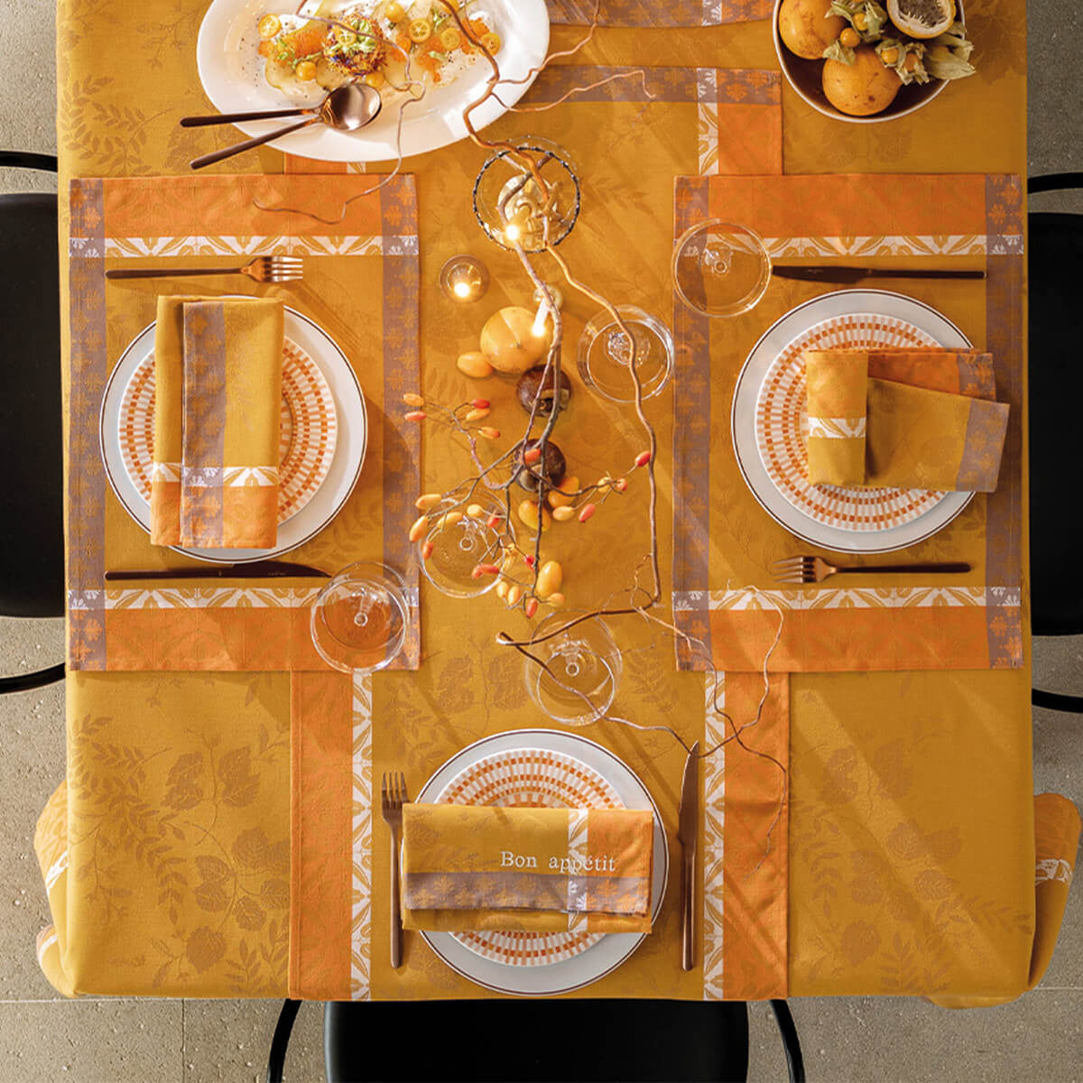 Overhead view of Orange Manor Lane tablecloth styled with matching placemats, napkins, and place settings.