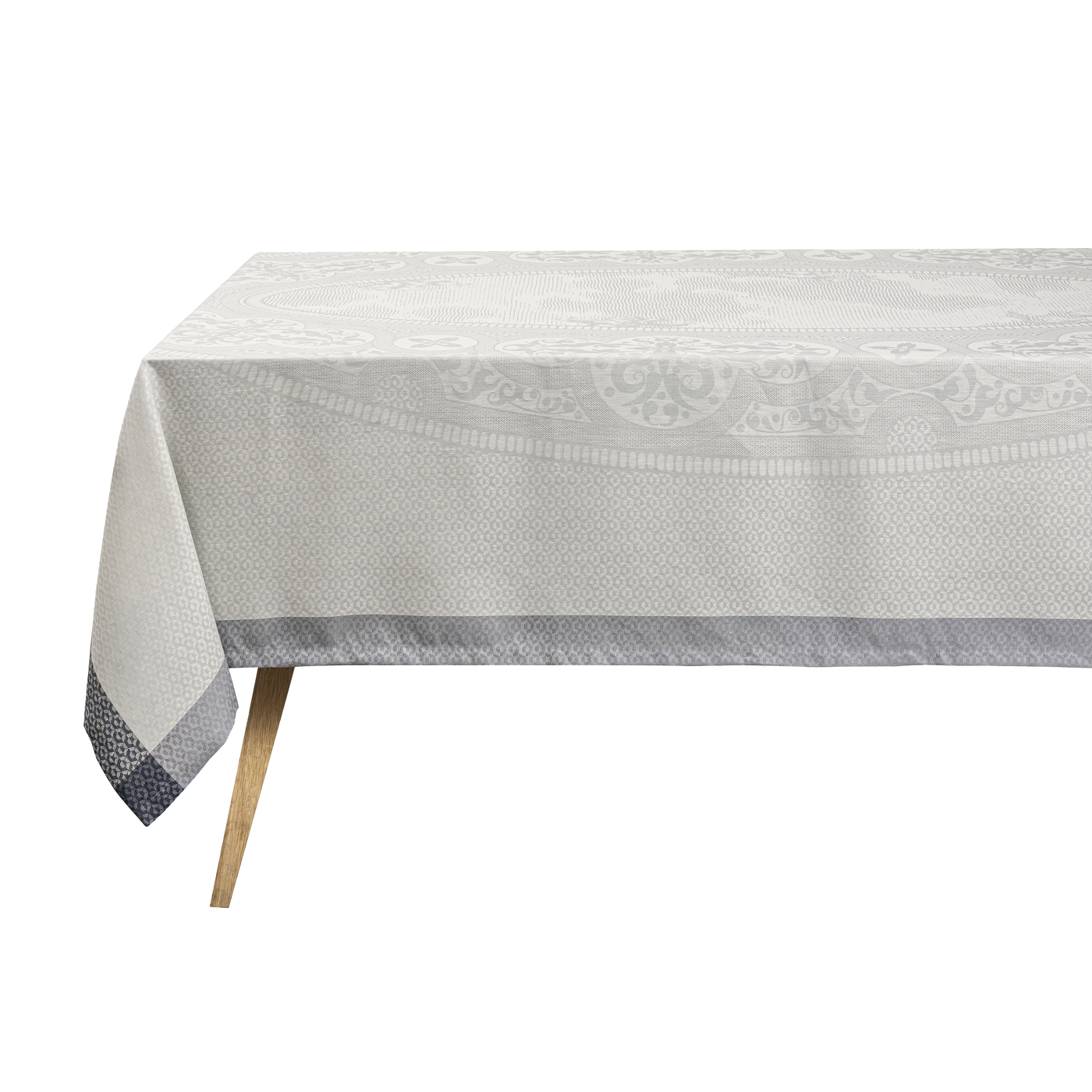 Le Jacquard Français Évasion Céleste ivory jacquard tablecloth with grey border on table.