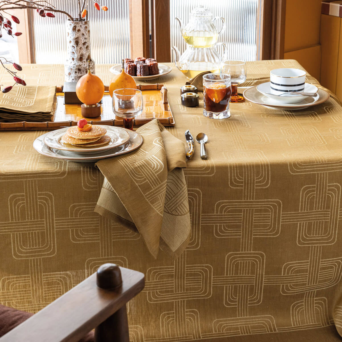 Le Jacquard Français Hôtel Particulier tablecloth in Brown, styled on a dining table with place settings.
