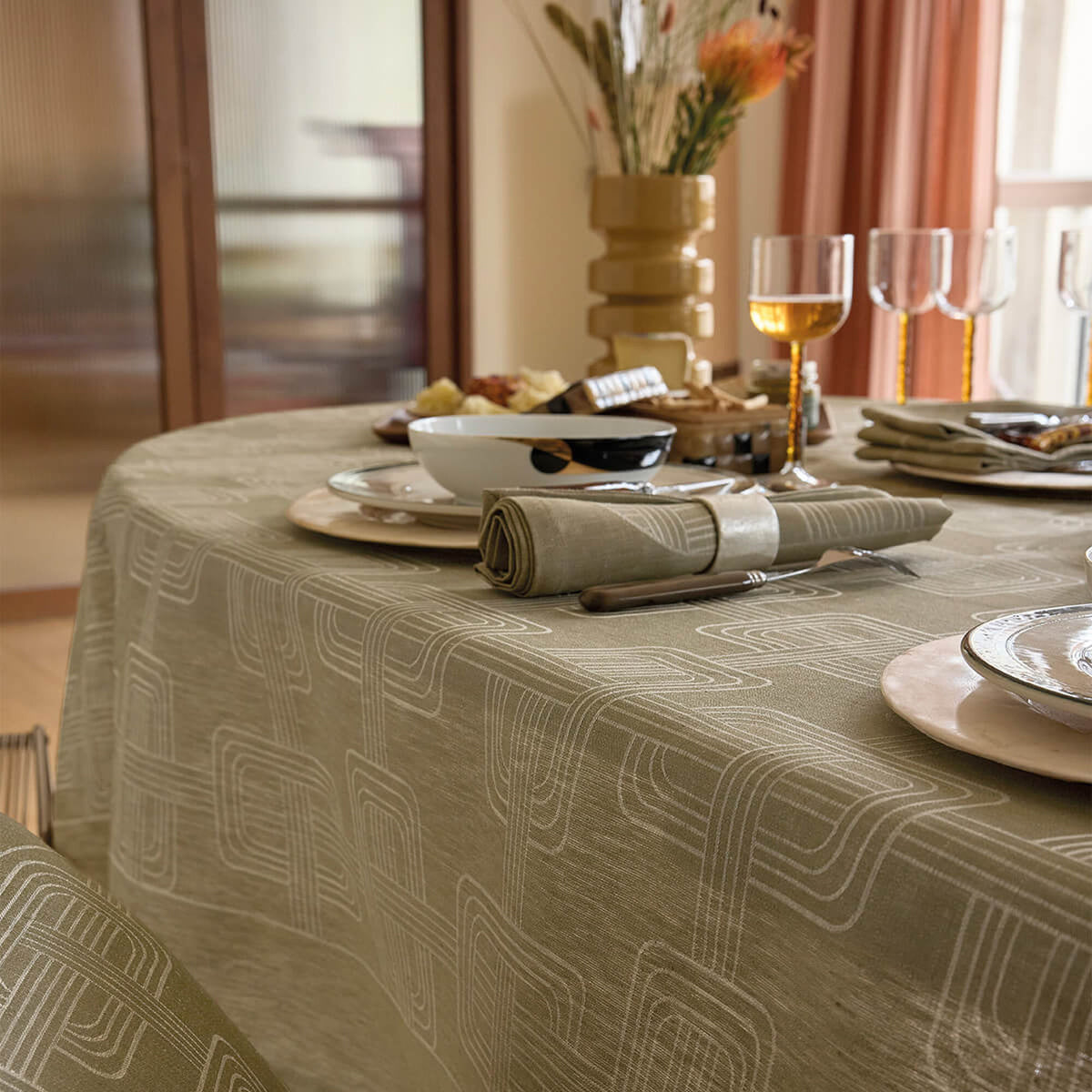 Draped oval table styled with place settings, showing Green jacquard pattern with geometric motifs.
