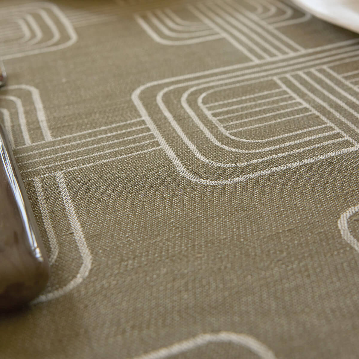 Close-up of Le Jacquard Français Hôtel Particulier tablecloth in Green, showing woven geometric line pattern.