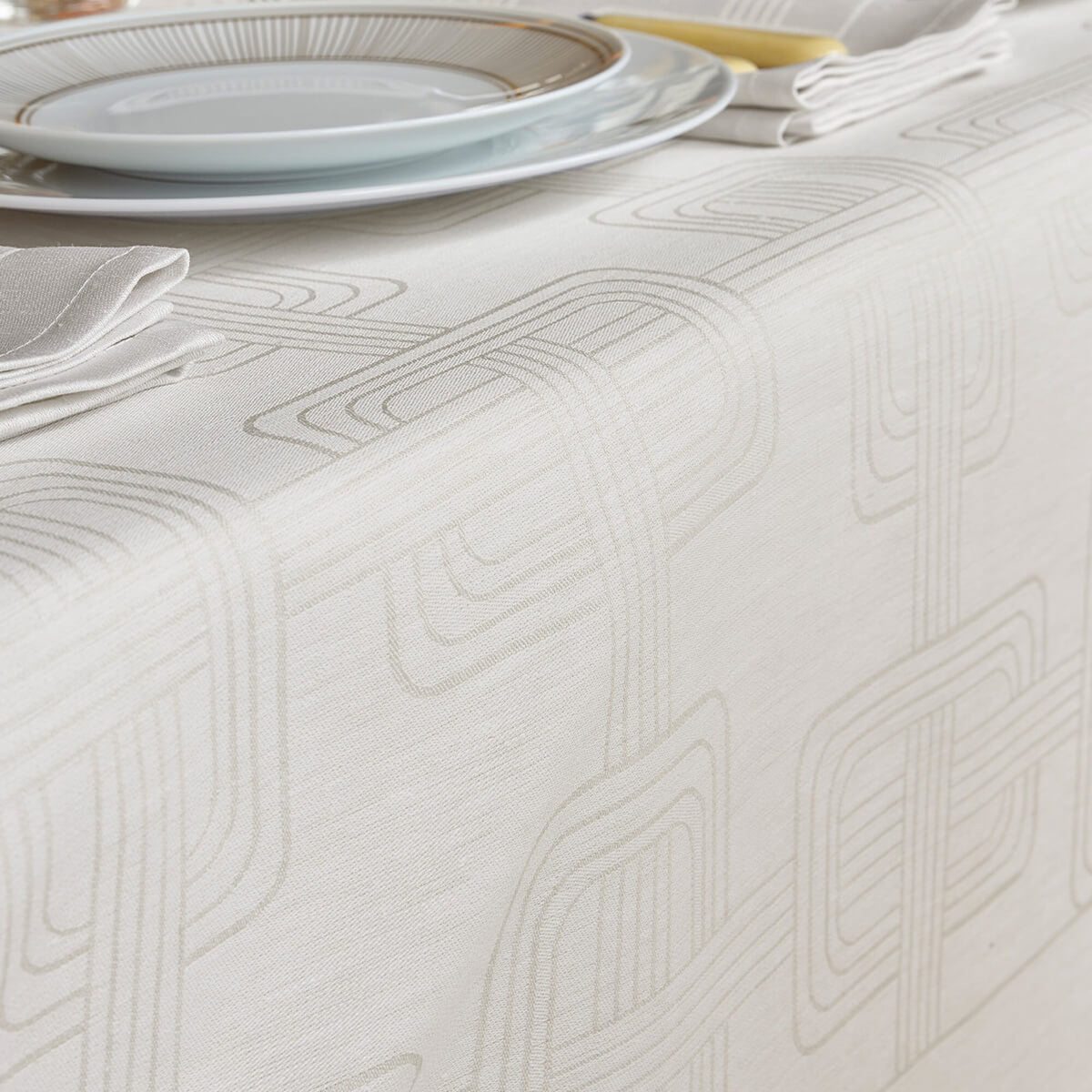 Close-up of Gray Le Jacquard Français Hôtel Particulier tablecloth with geometric jacquard pattern, styled with plates.