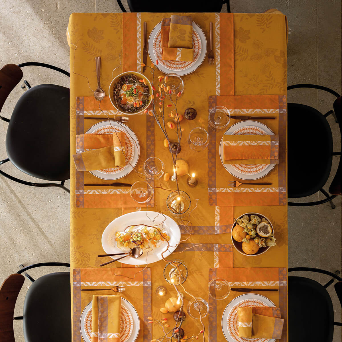 Overhead view of Orange Manor Lane tablecloth styled with matching placemats, napkins, and place settings.
