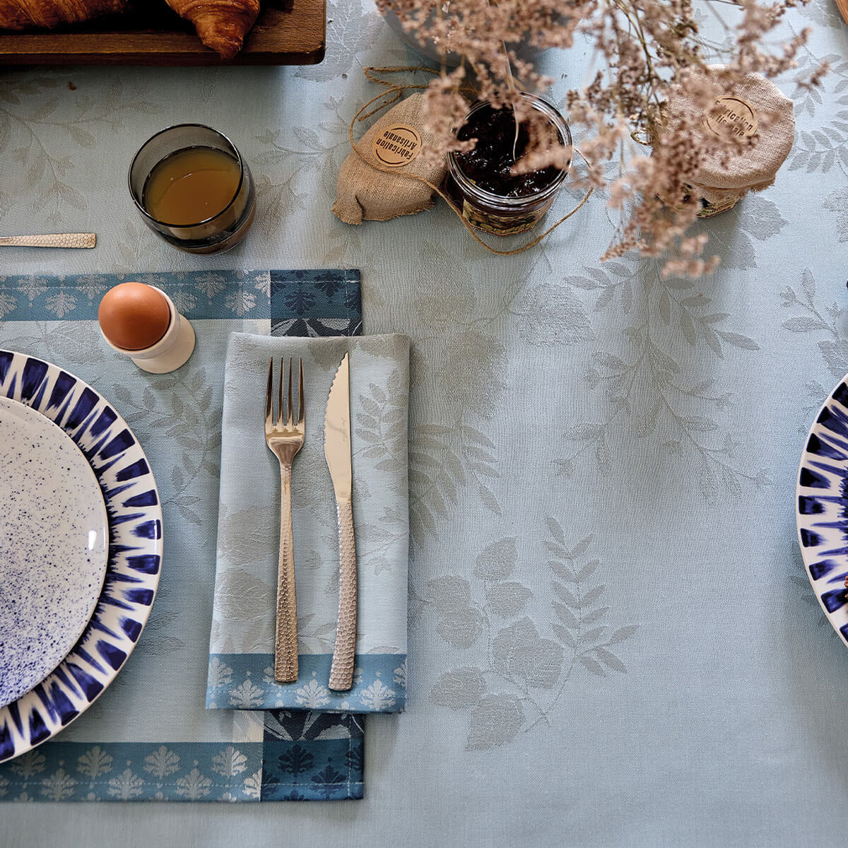 Overhead view of Blue Manor Lane tablecloth and napkin styled with blue-rimmed plates and breakfast setting.