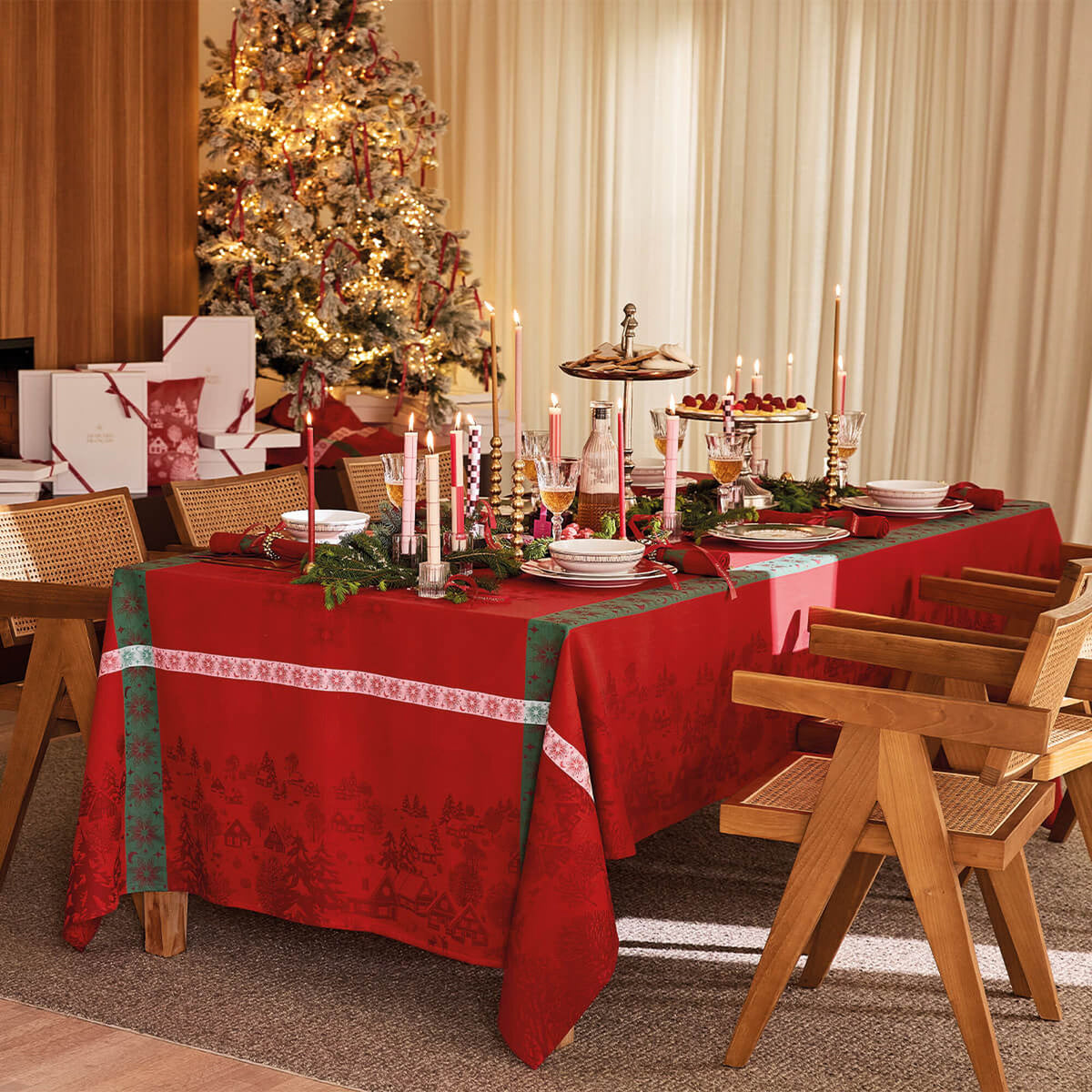 Red Sous les Étoiles tablecloth styled on holiday dining table with Christmas tree backdrop.