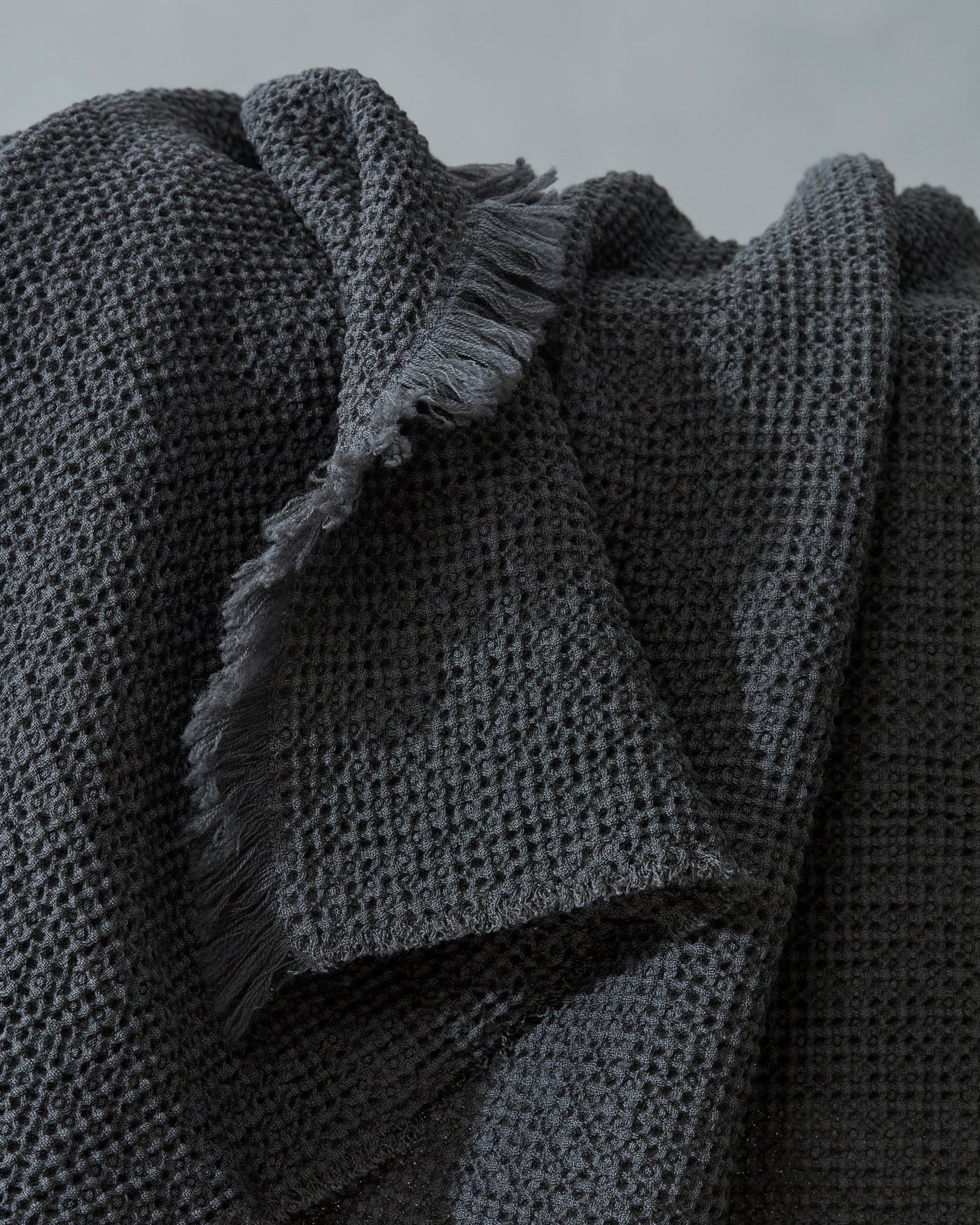 Close-up of charcoal waffle-weave texture with frayed edges on Society Limonta Nid blanket.