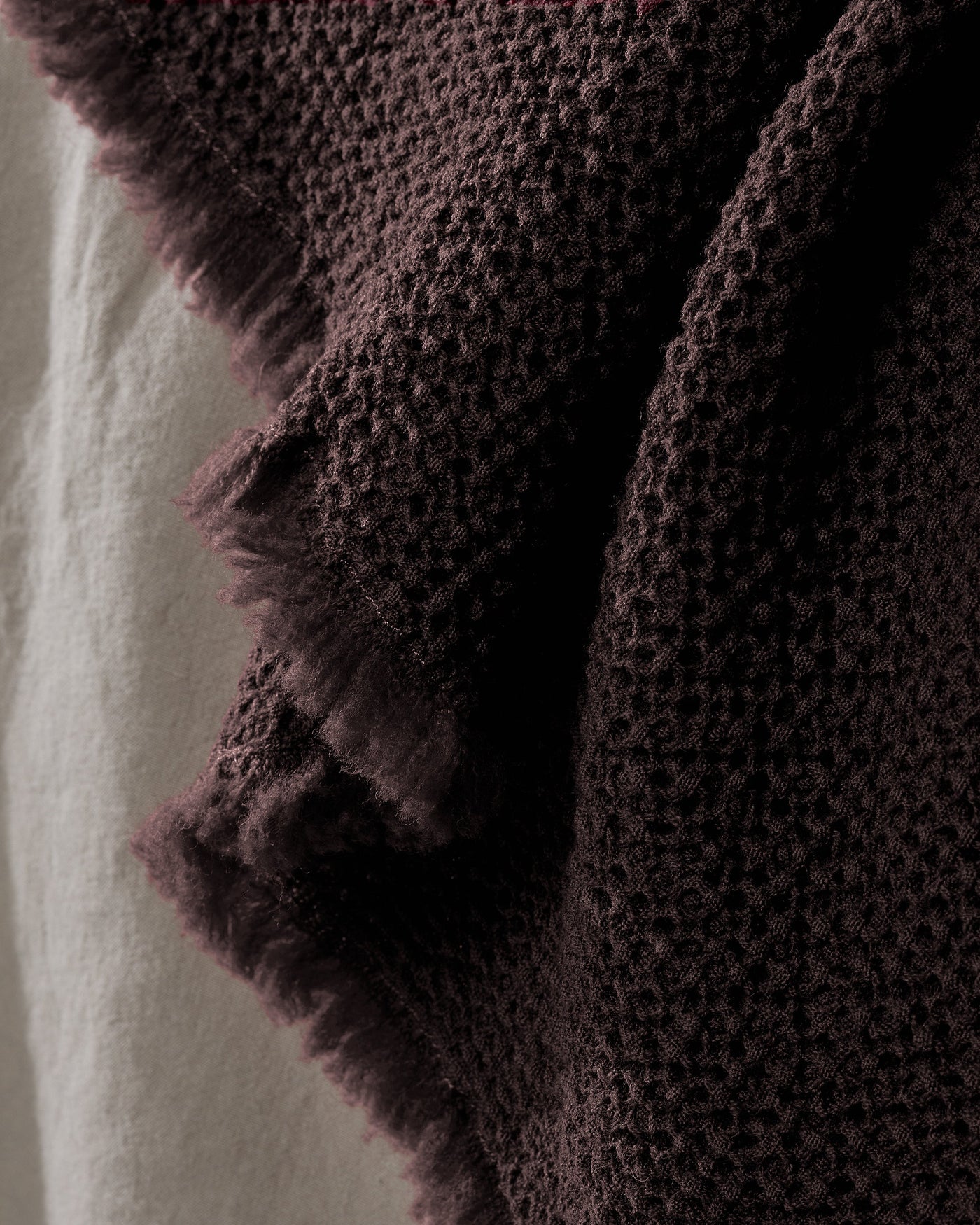 Close-up of Society Limonta Nid blanket showing plum waffle-knit texture and frayed edge detail.