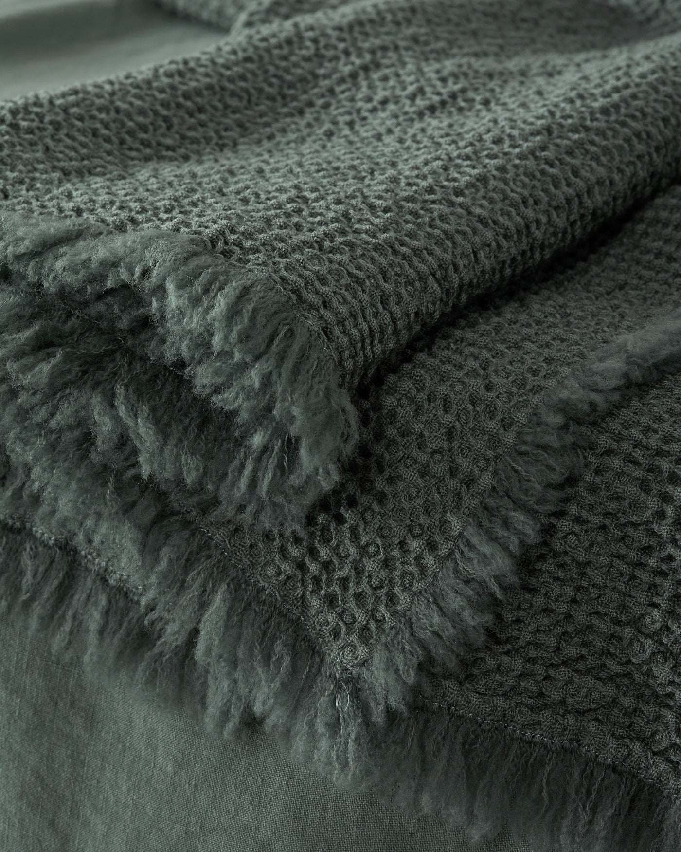 Close-up of Society Limonta Nid blanket fringe edge in deep forest green waffle weave.