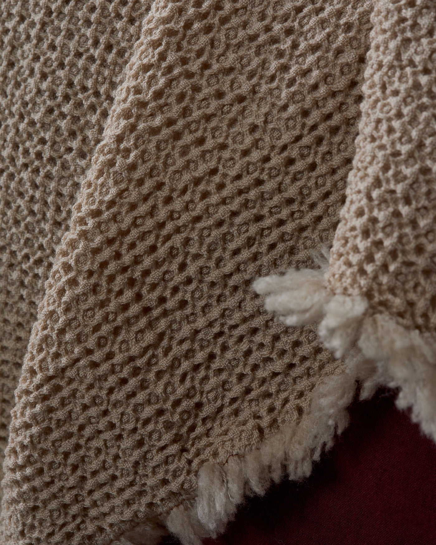 Close-up of Society Limonta Nid blanket honeycomb weave texture in sand with ivory fringe detail.