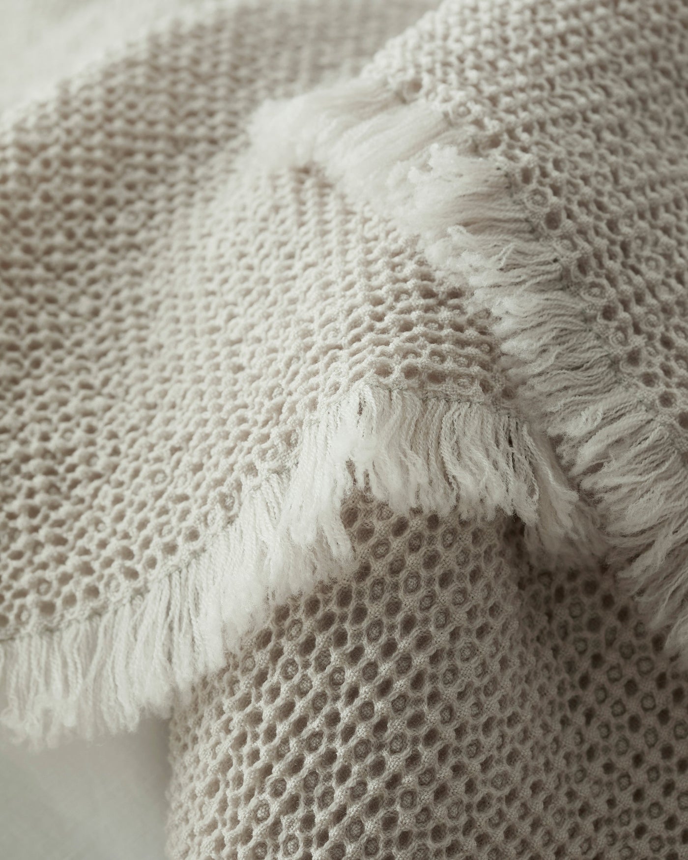 Close-up of Society Limonta Nid blanket honeycomb weave with fringe edge in sand.