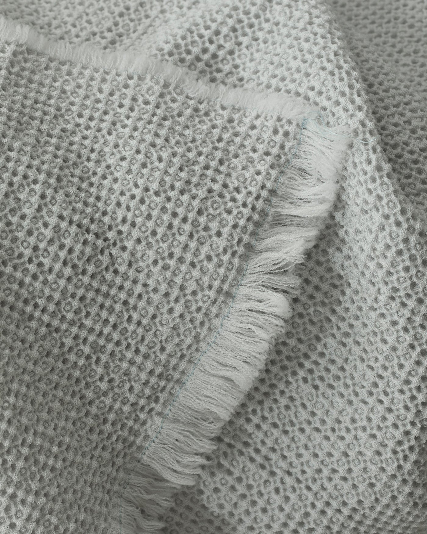 Close-up of Society Limonta Nid blanket's honeycomb weave texture and fringe edge in silver grey.