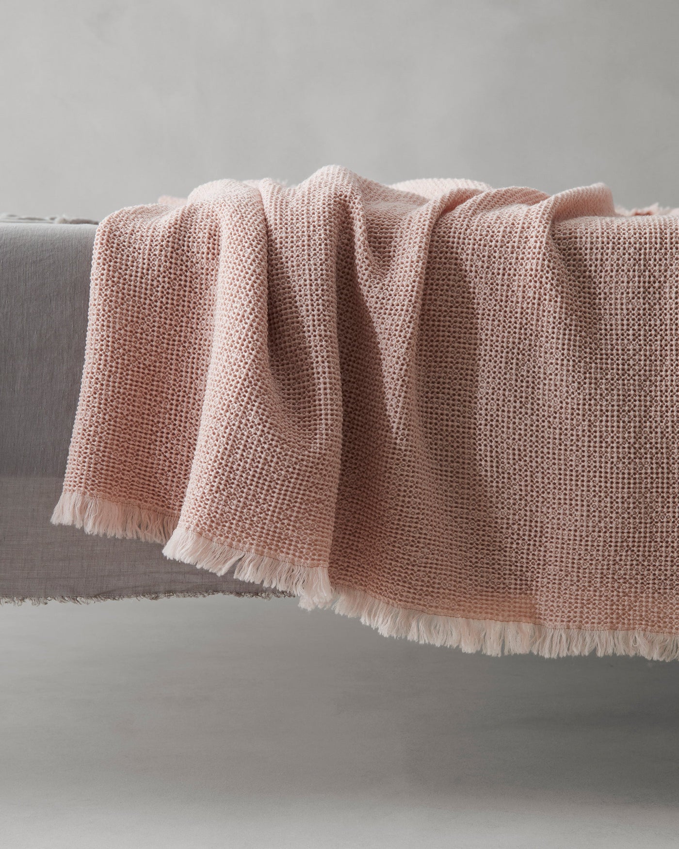 Close-up of Society Limonta Nid blanket in blush, showing woven texture and fringe trim.
