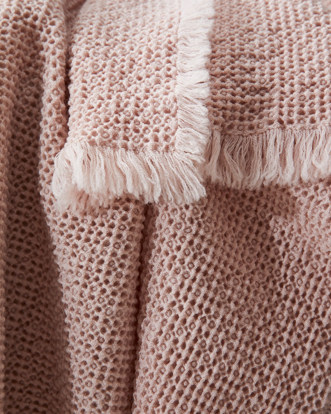 Close-up of Society Limonta Nid blanket blush fringe trim and waffle-knit texture.