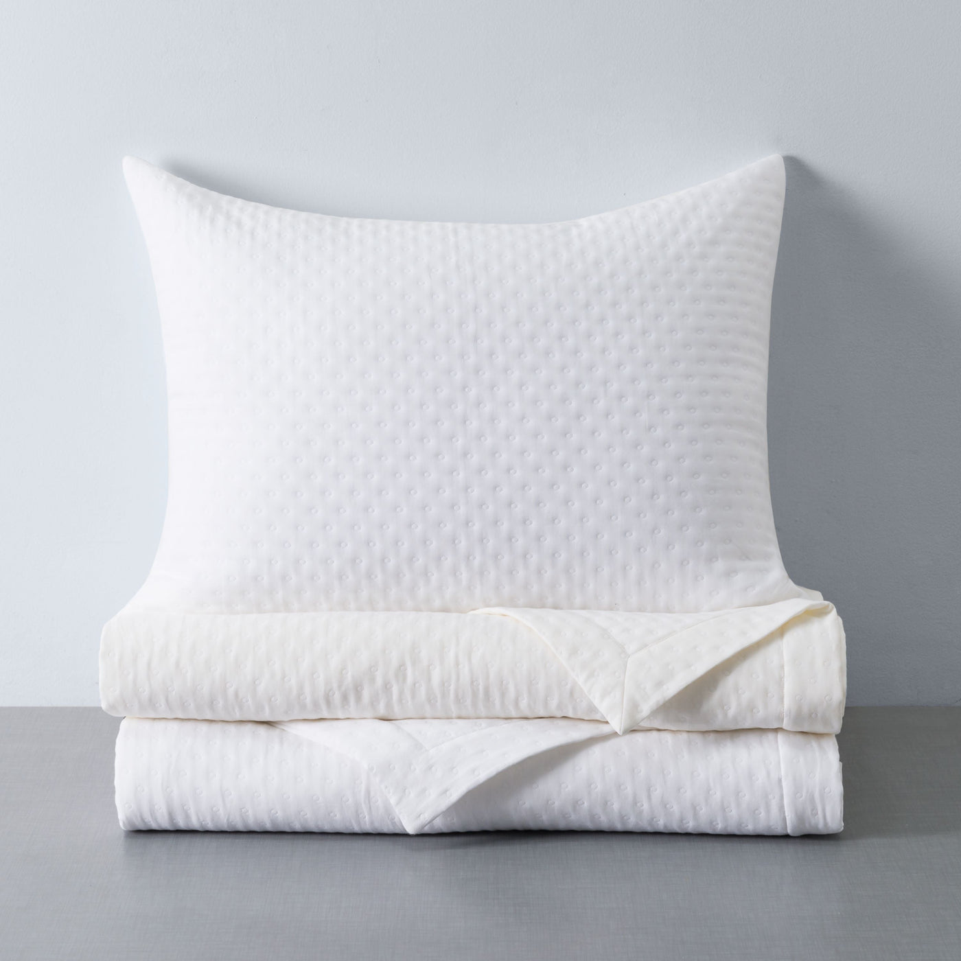 Home Treasures Nimbus ivory quilted yardage and pillow with diamond texture, neatly folded.
