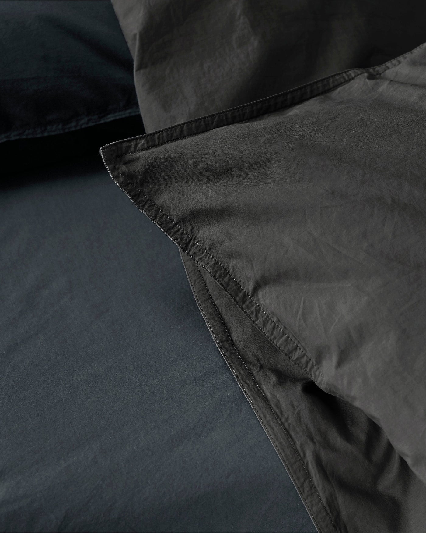 Close-up of Society Limonta Nite duvet cover hem in charcoal cotton, showing texture and stitching detail.