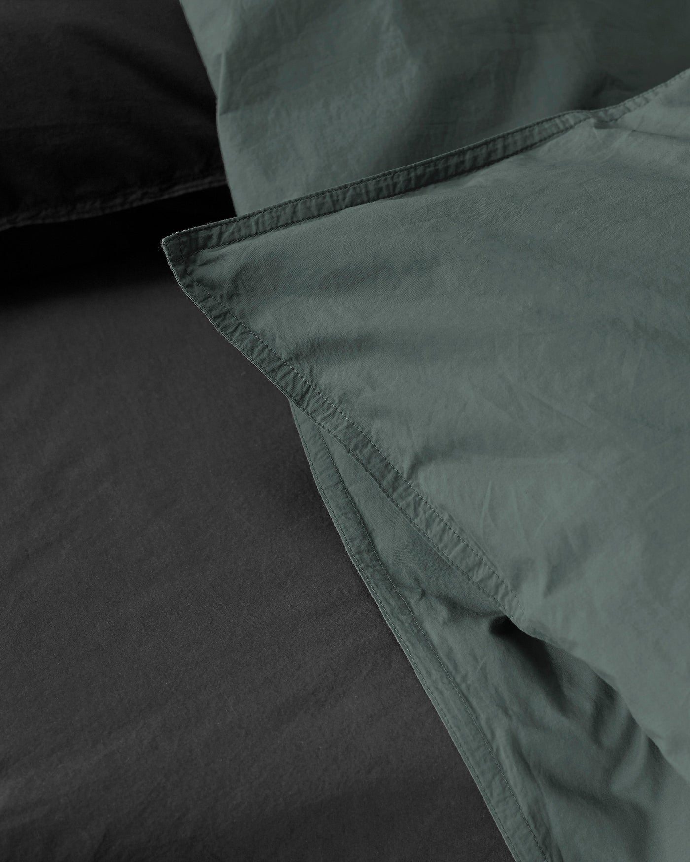 Close-up of sage and charcoal cotton duvet cover corner seam detail.