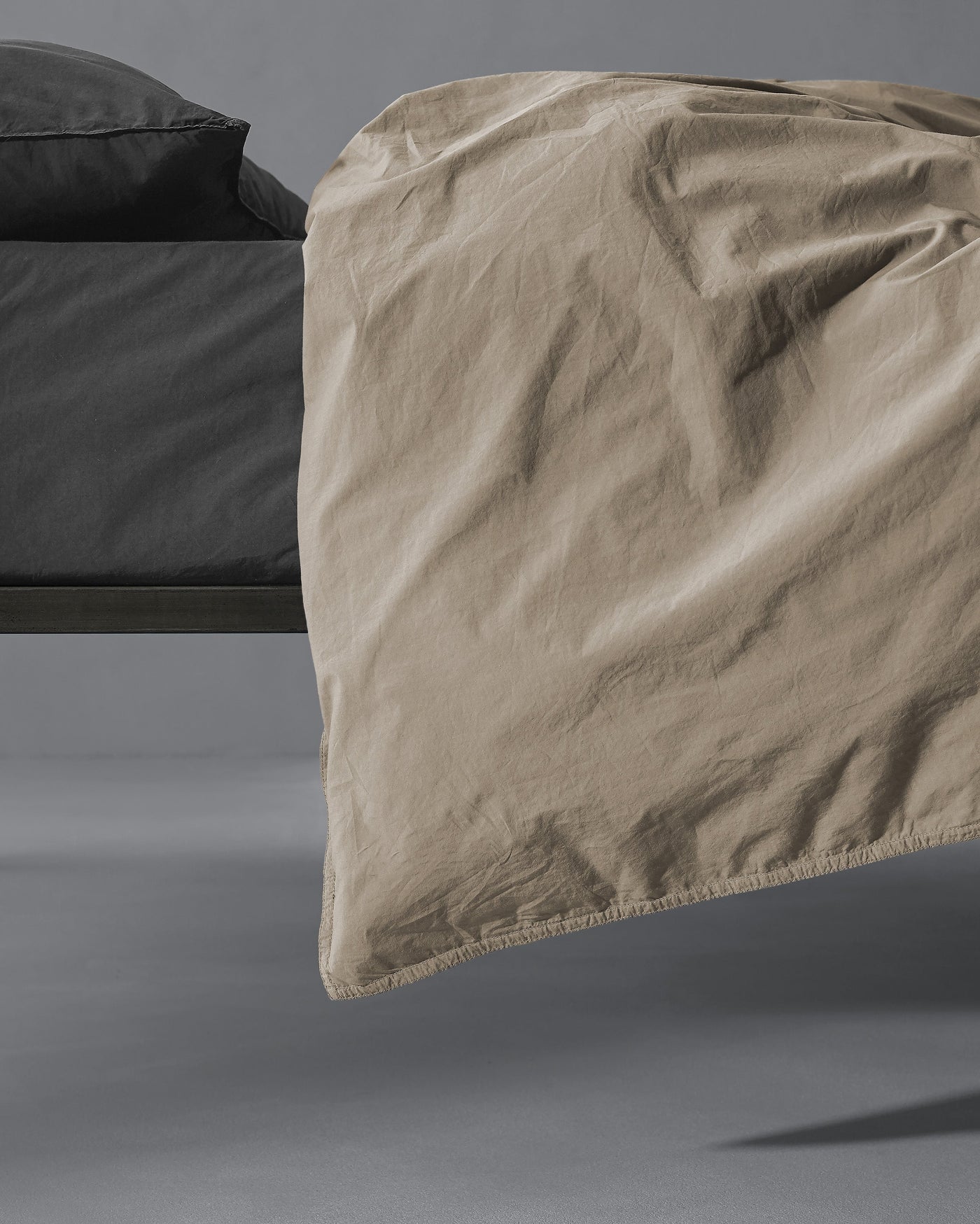 Corner detail of Society Limonta Nite duvet cover in sand, showing relaxed drape and stitched edge.