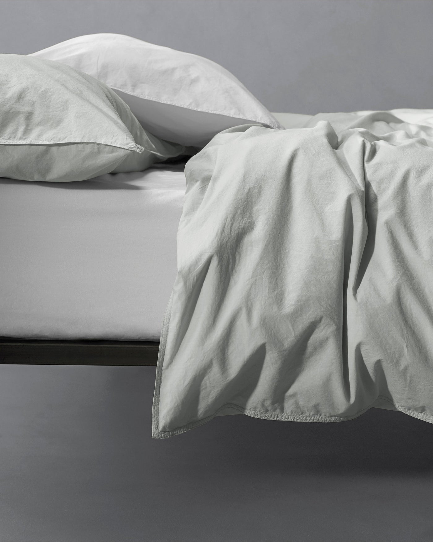 Draped duvet cover edge showing relaxed linen-cotton texture in mist.