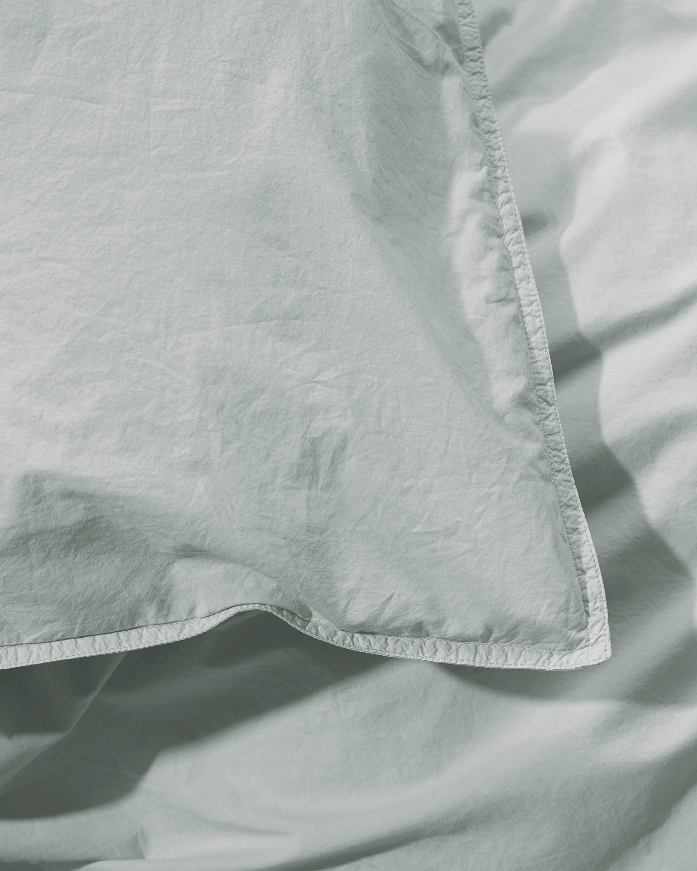 Close-up of Society Limonta Nite duvet cover corner seam in sage linen.
