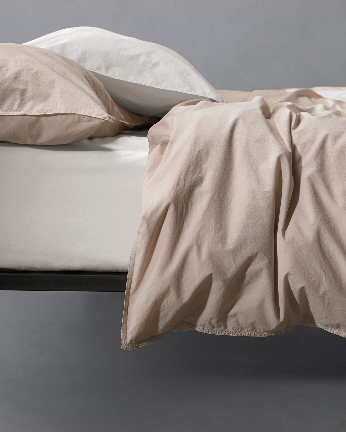 Society Limonta Nite duvet cover in sand draped over bed edge, relaxed linen texture visible.