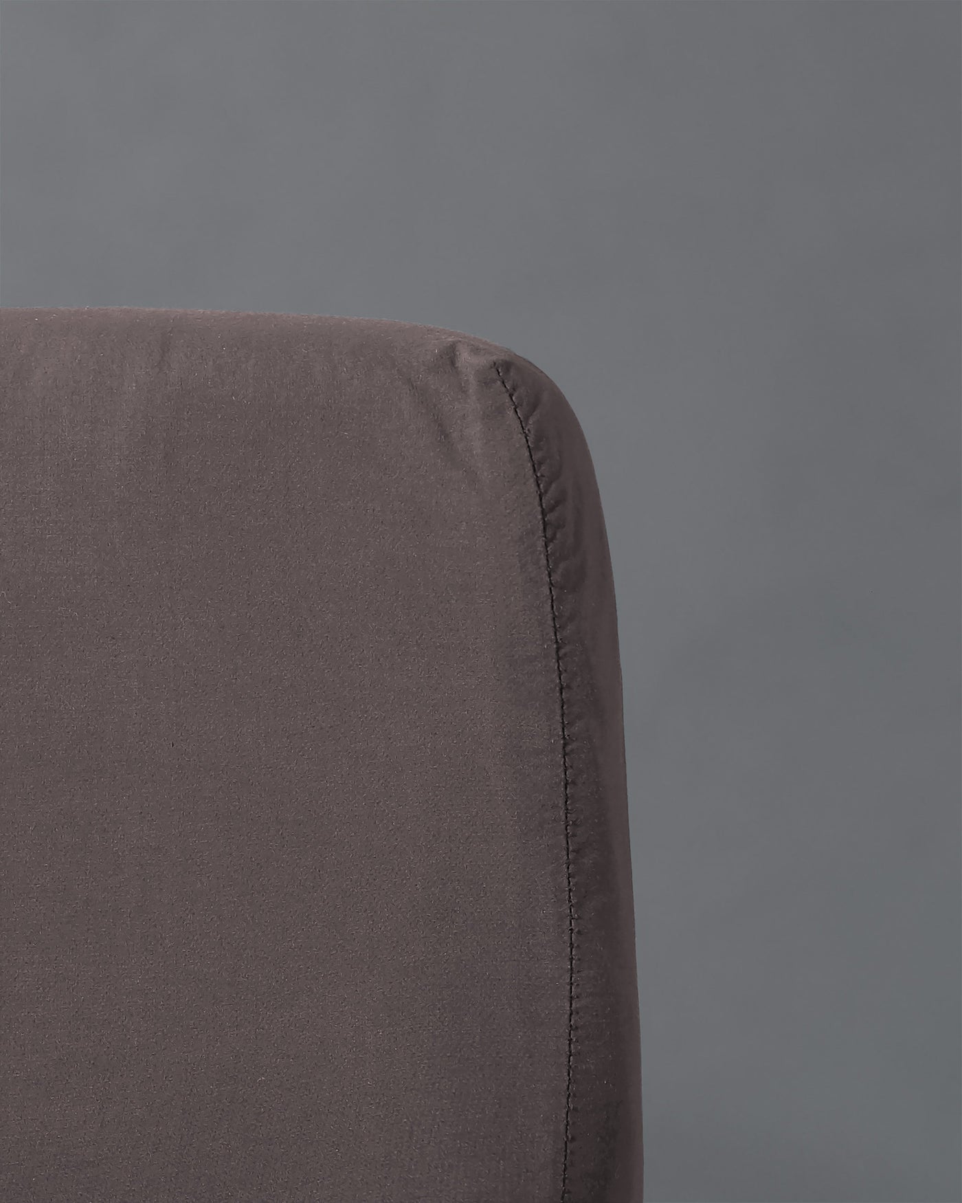 Close-up of charcoal fitted sheet corner showing seam detail and matte linen texture.
