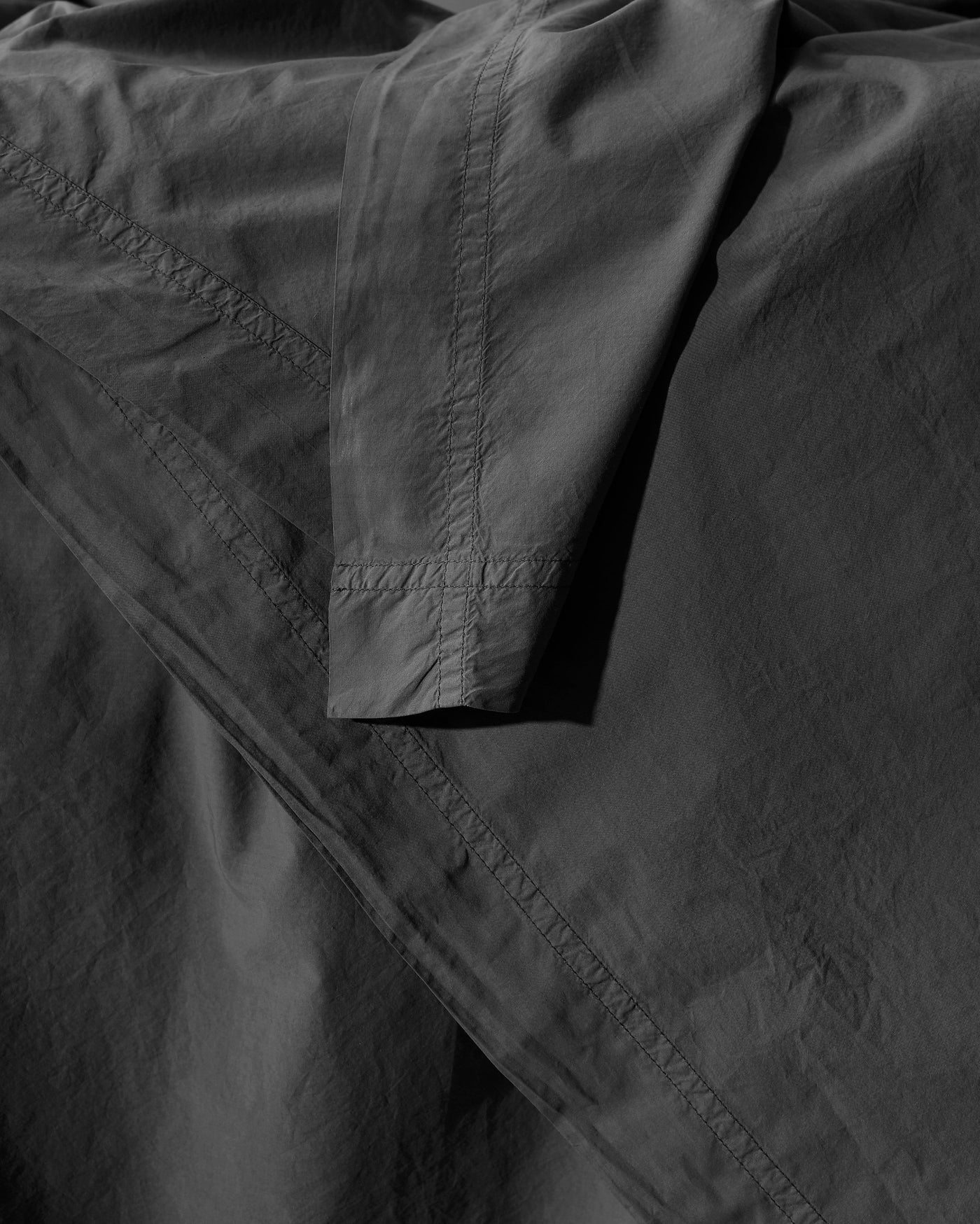 Close-up of Society Limonta Nite duvet cover hem stitching in charcoal.