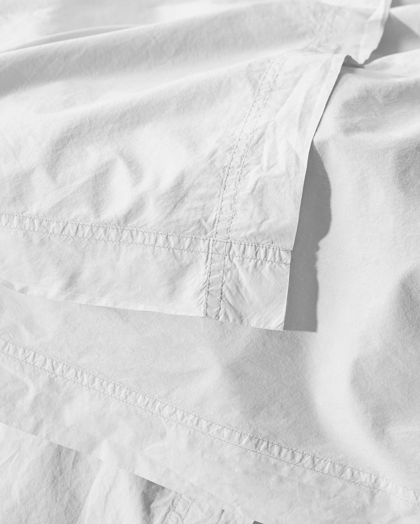 Close-up of white cotton duvet cover with decorative ladder-stitch hemstitching detail.