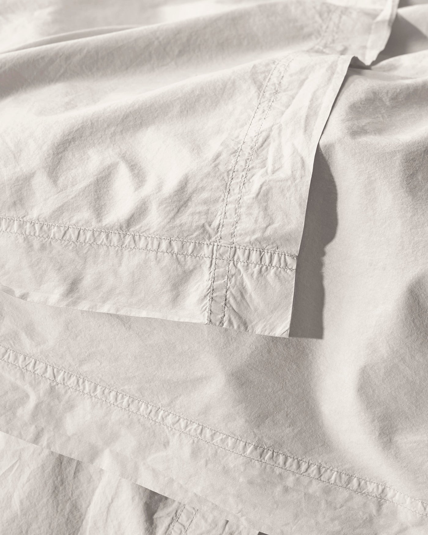 Close-up of ivory cotton duvet cover showing delicate ladder stitch hem detail.