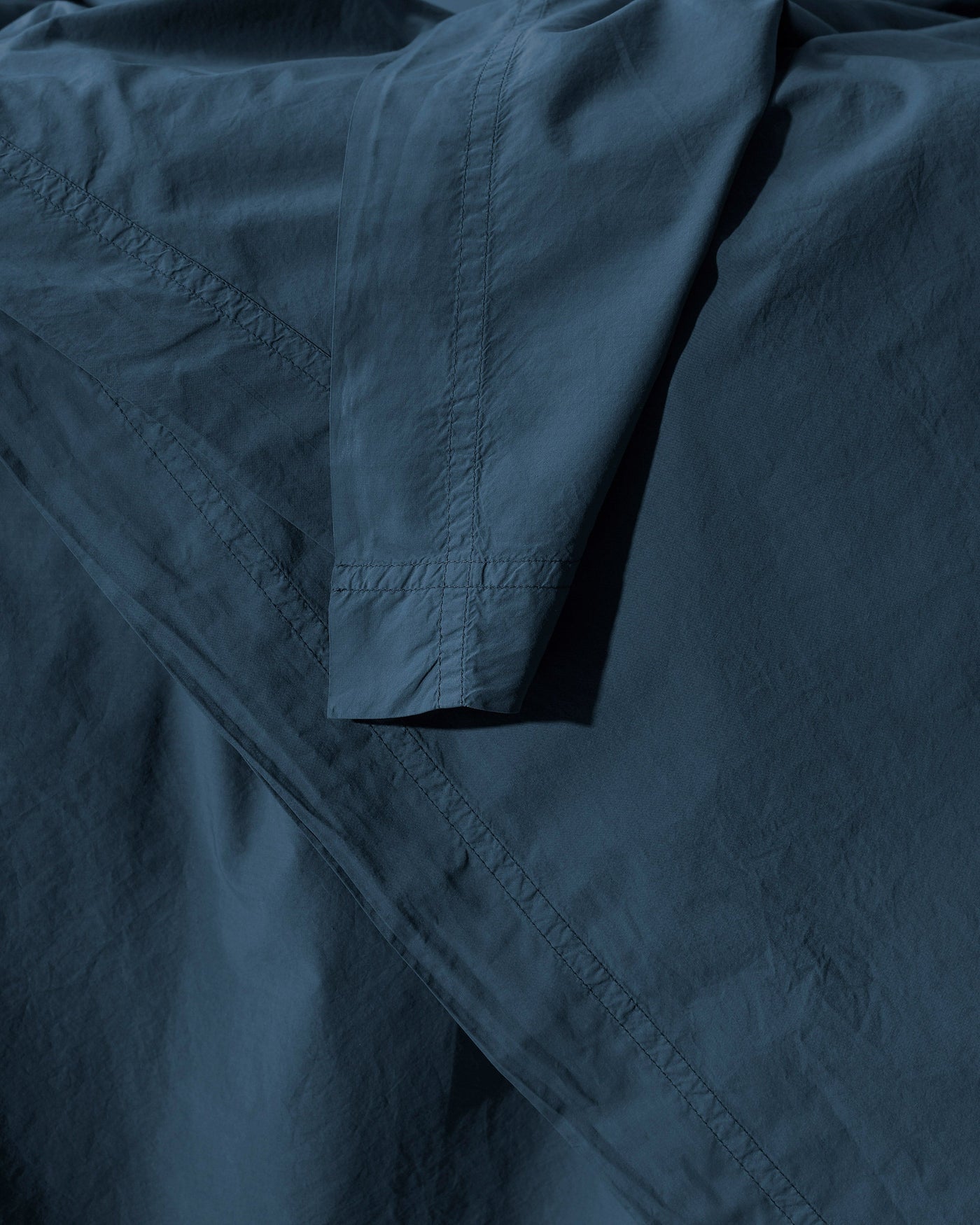 Close-up of Society Limonta Nite duvet cover hem stitching in deep teal cotton.