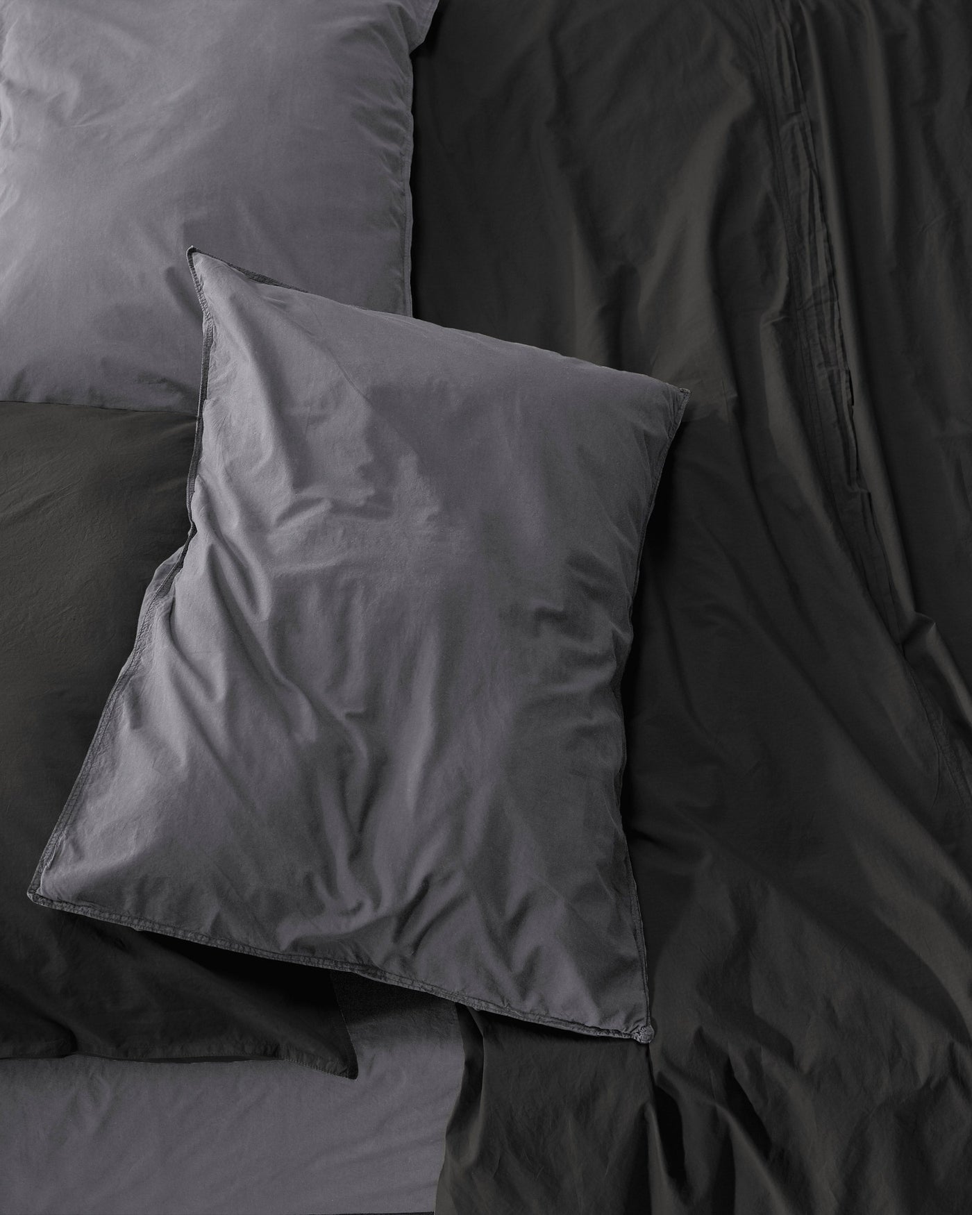 Close-up overhead view of charcoal cotton pillowcases with soft natural drape.