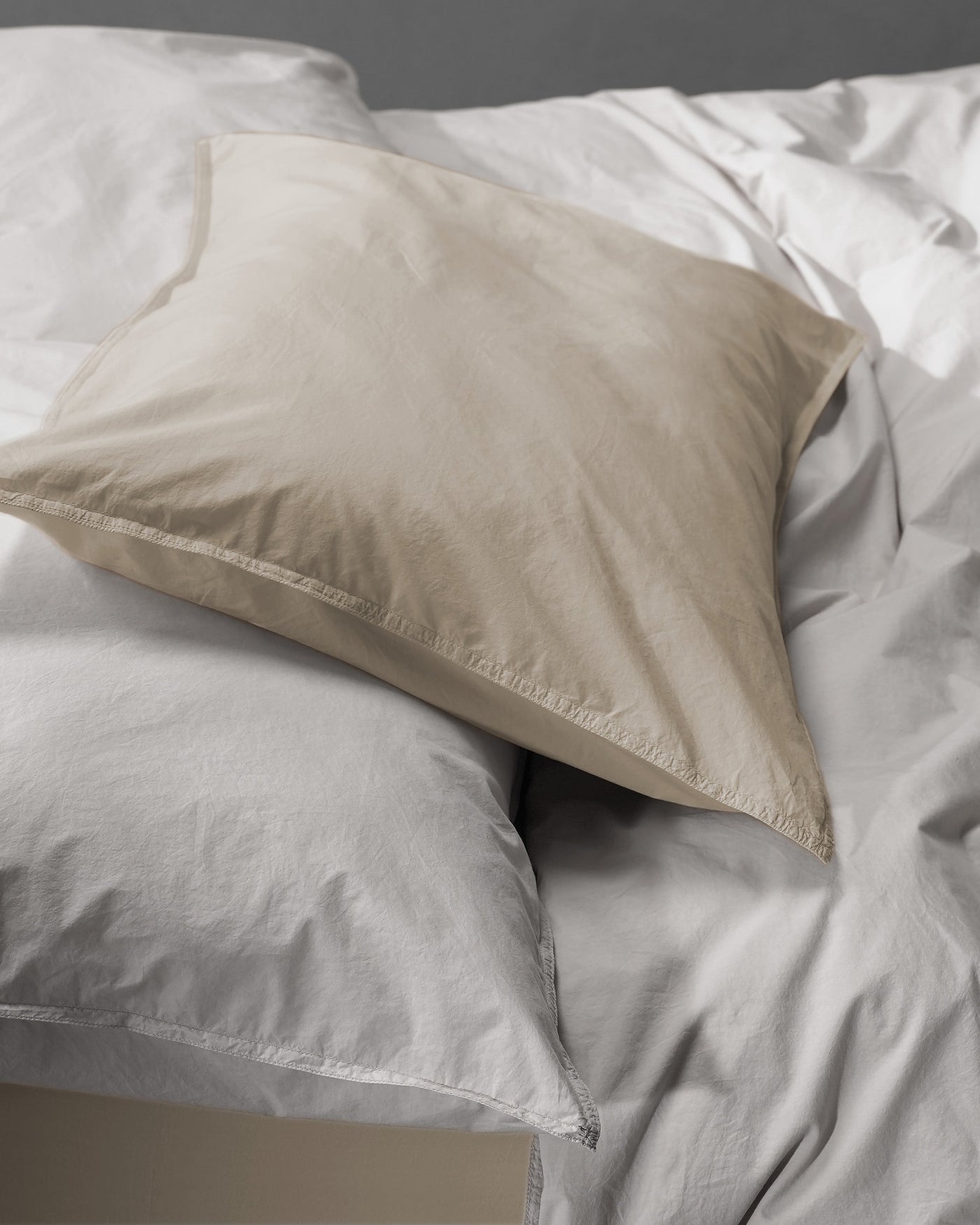 Sand-toned pillowcase atop white bedding, showing contrast and relaxed cotton texture.