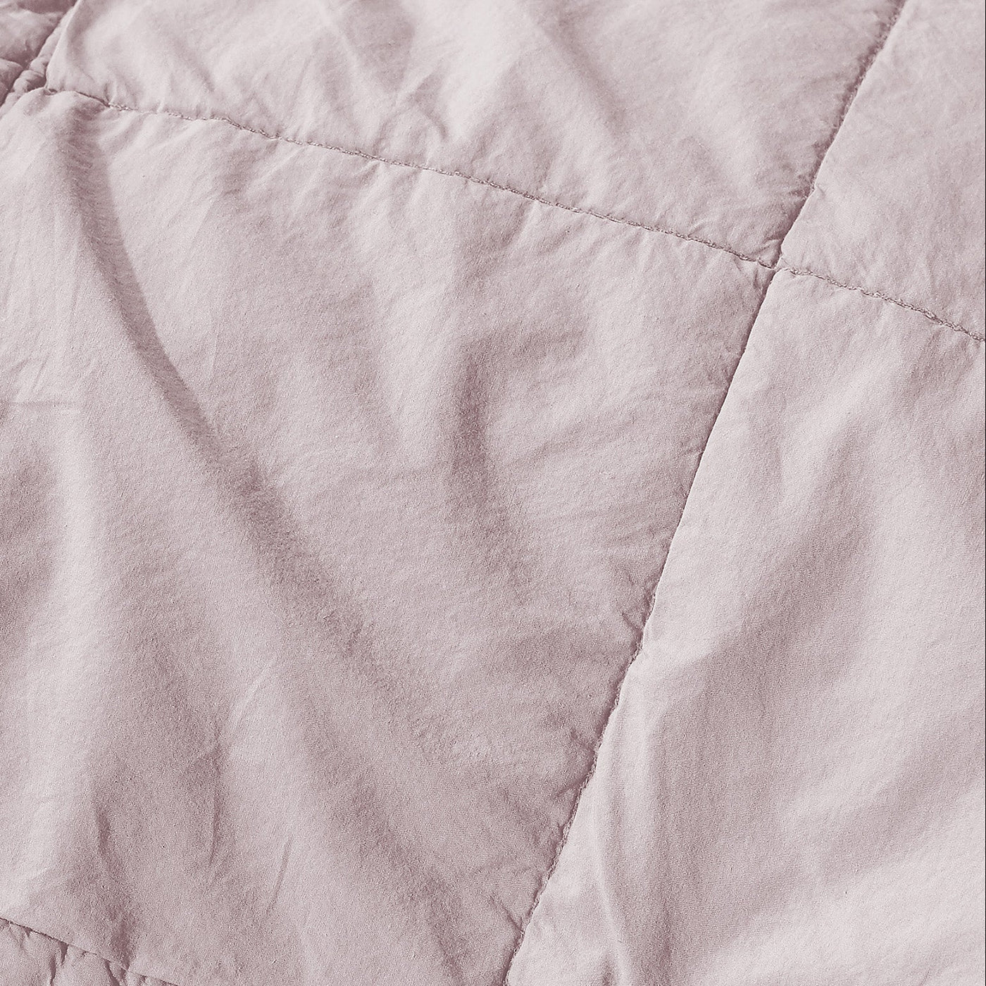 Close-up of blush cotton quilt showing diamond quilting stitches and soft washed texture.
