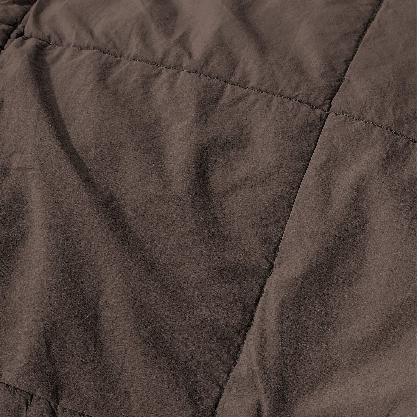 Close-up of chocolate linen quilt showing diamond stitching pattern and softly rumpled texture.