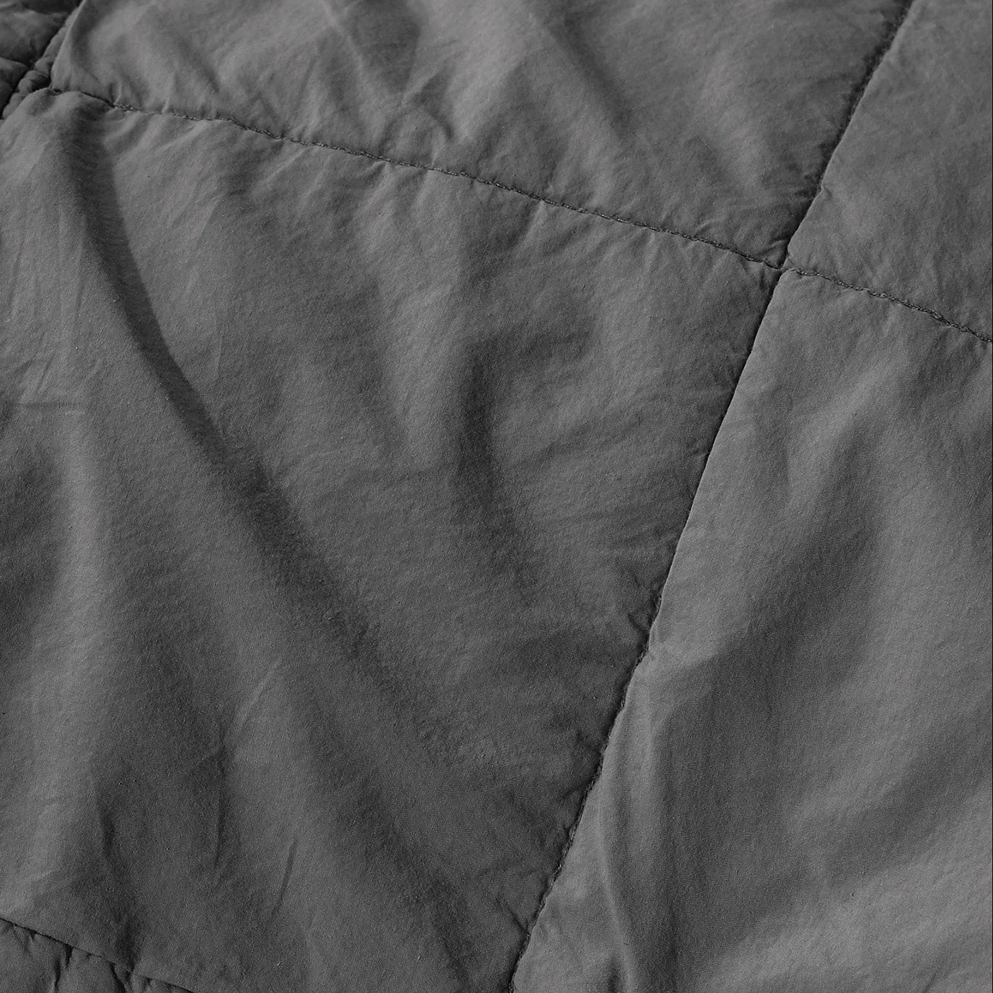 Close-up of charcoal linen quilt stitching detail with softly rumpled texture.