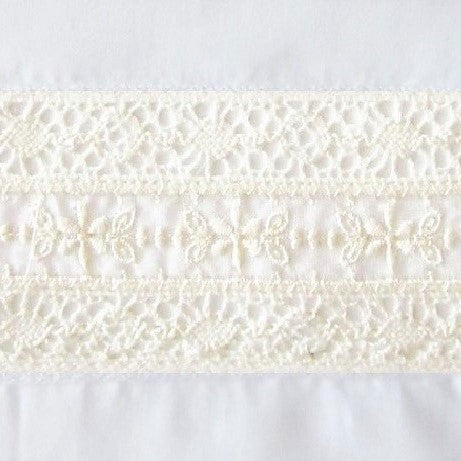 Close-up of ivory cotton lace trim with floral embroidery detail on white fabric.
