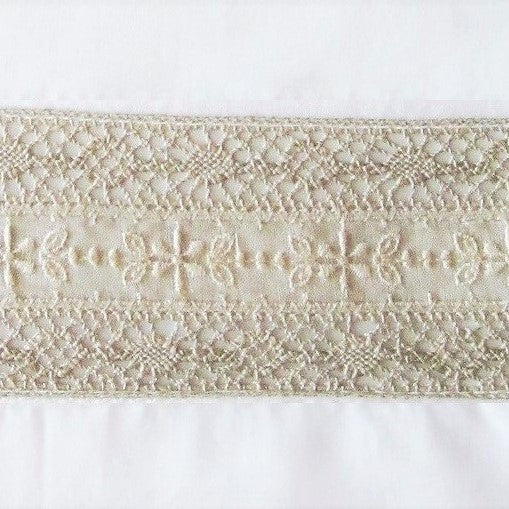 Close-up of ivory lace trim with floral embroidery on a white linen pillow sham.