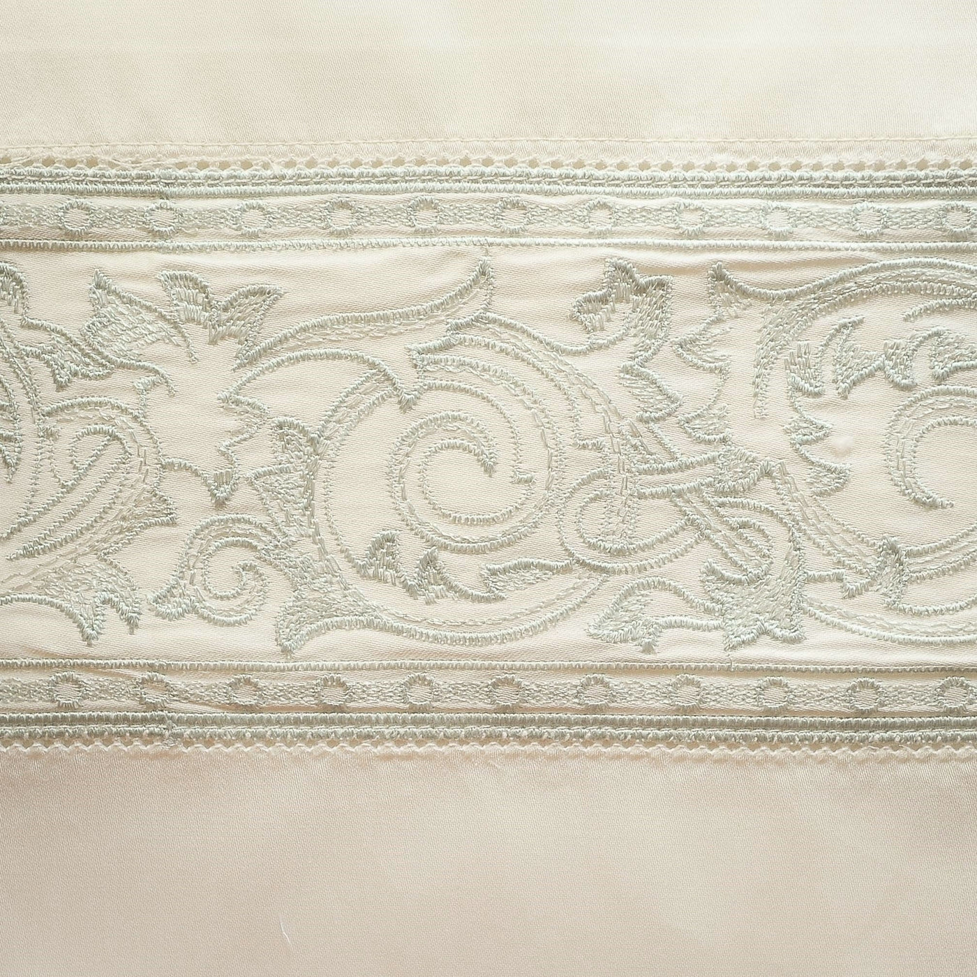 Close-up of ivory flat sheet hem with silver scrolling acanthus embroidery and lace trim border.