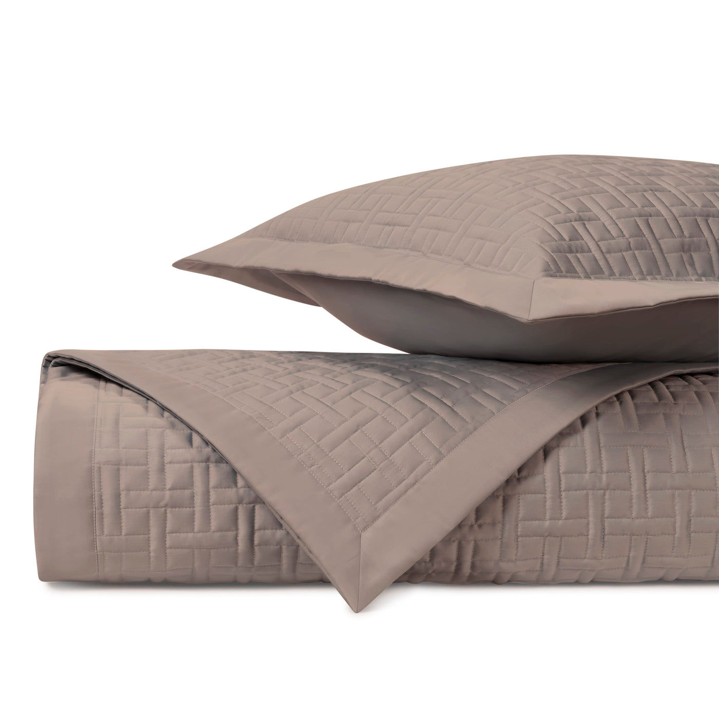 Close-up of taupe quilted parquet-pattern coverlet and sham, showing geometric basketweave stitching.